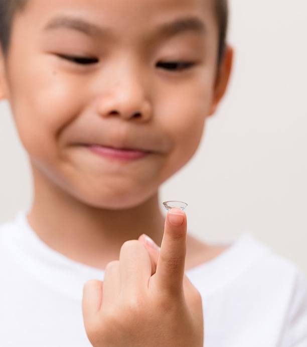 Child looking at contact lens on finger