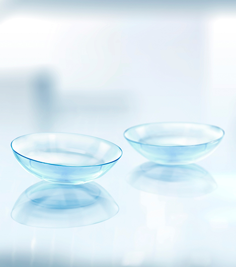 Two clear contact lenses resting on a flat surface