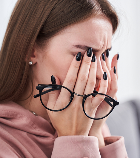 Woman taking off her glasses to rub her eyes