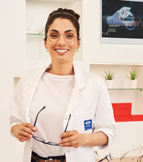 Smiling woman in white coat holding reading glasses