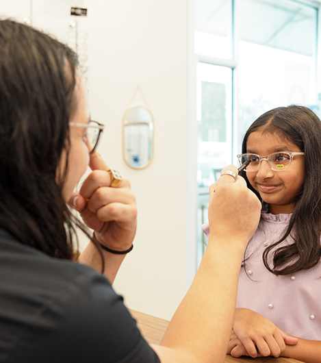 Young girl in optometry office trying on glasses