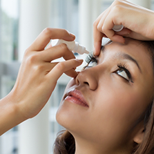 Person placing eye drops in their eye