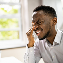 Man wincing in pain and closing his eye