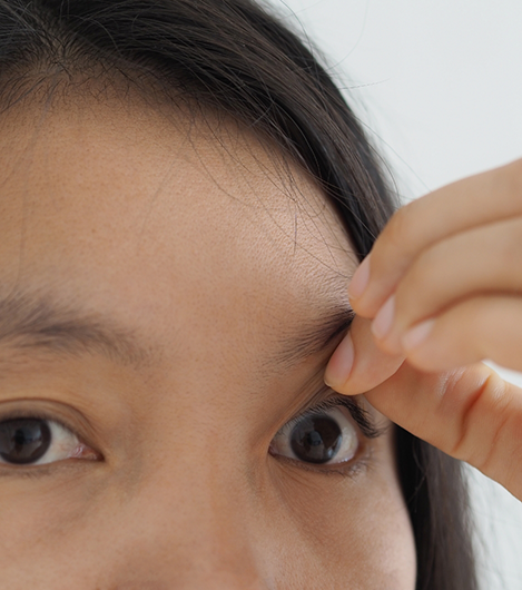 Woman lifting her upper eyelid to look at her eye