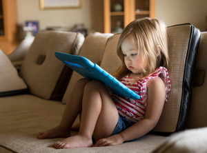 Little girl in striped shirt staring at tablet